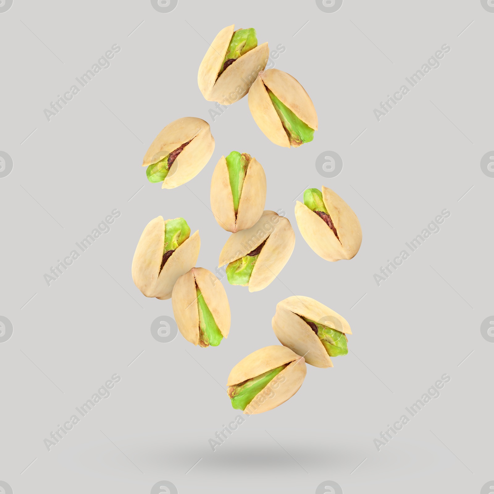 Image of Tasty pistachios falling on light grey background