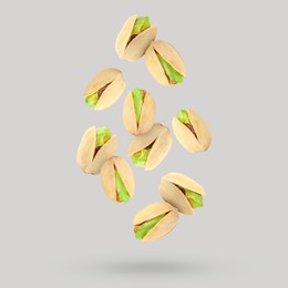 Image of Tasty pistachios falling on light grey background