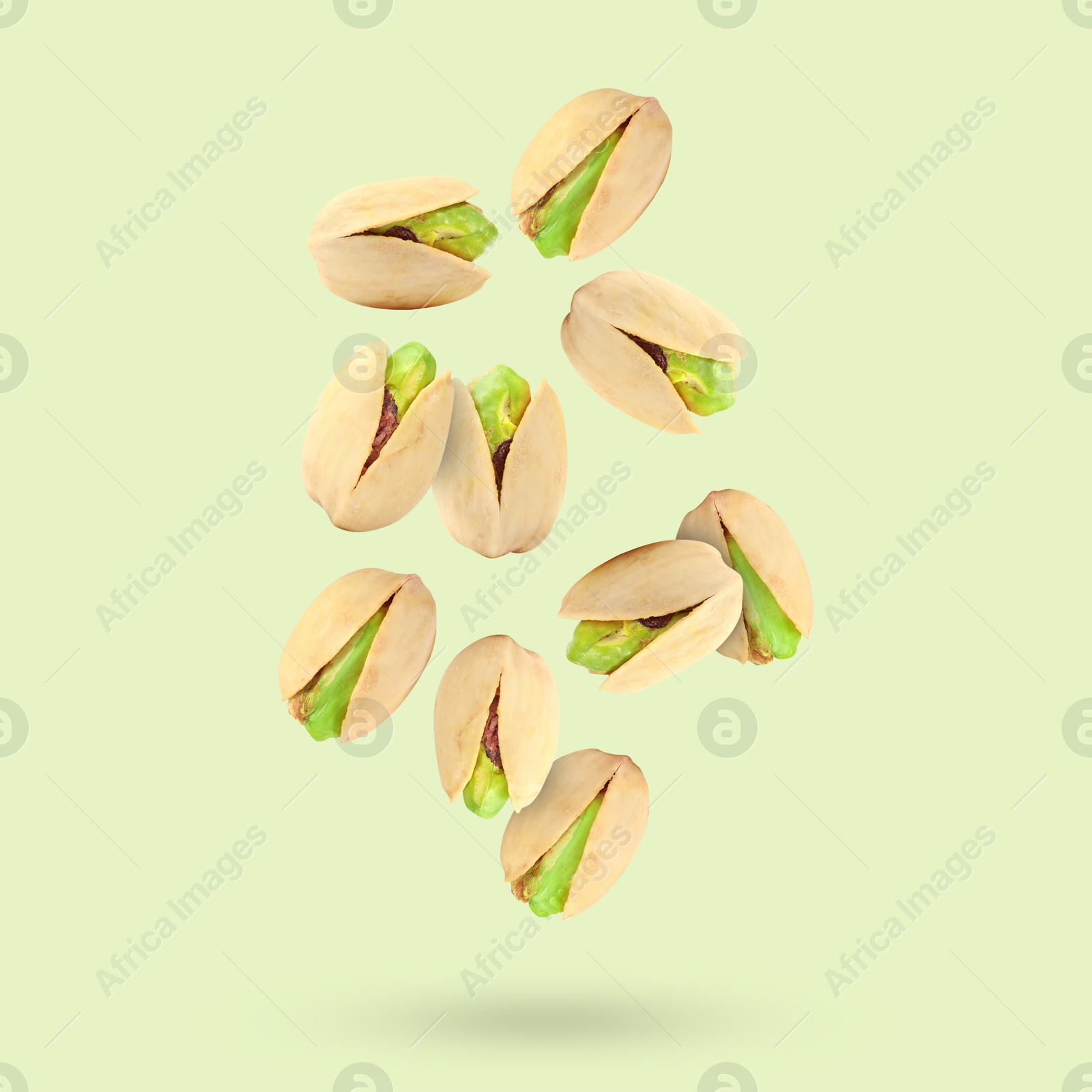 Image of Tasty pistachios in air on color background