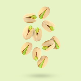 Tasty pistachios in air on color background