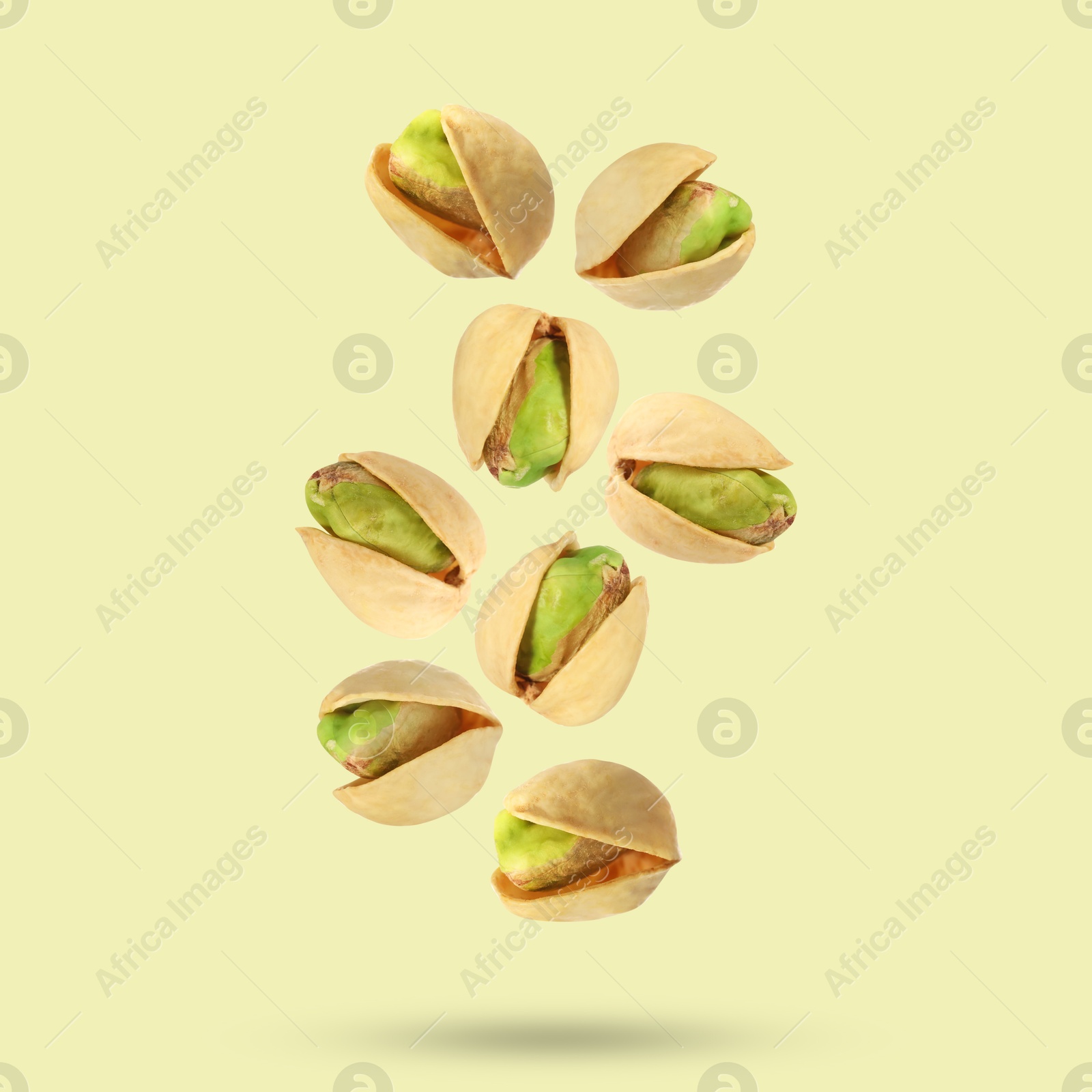 Image of Tasty pistachios in air on color background