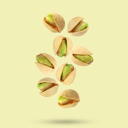 Tasty pistachios in air on color background