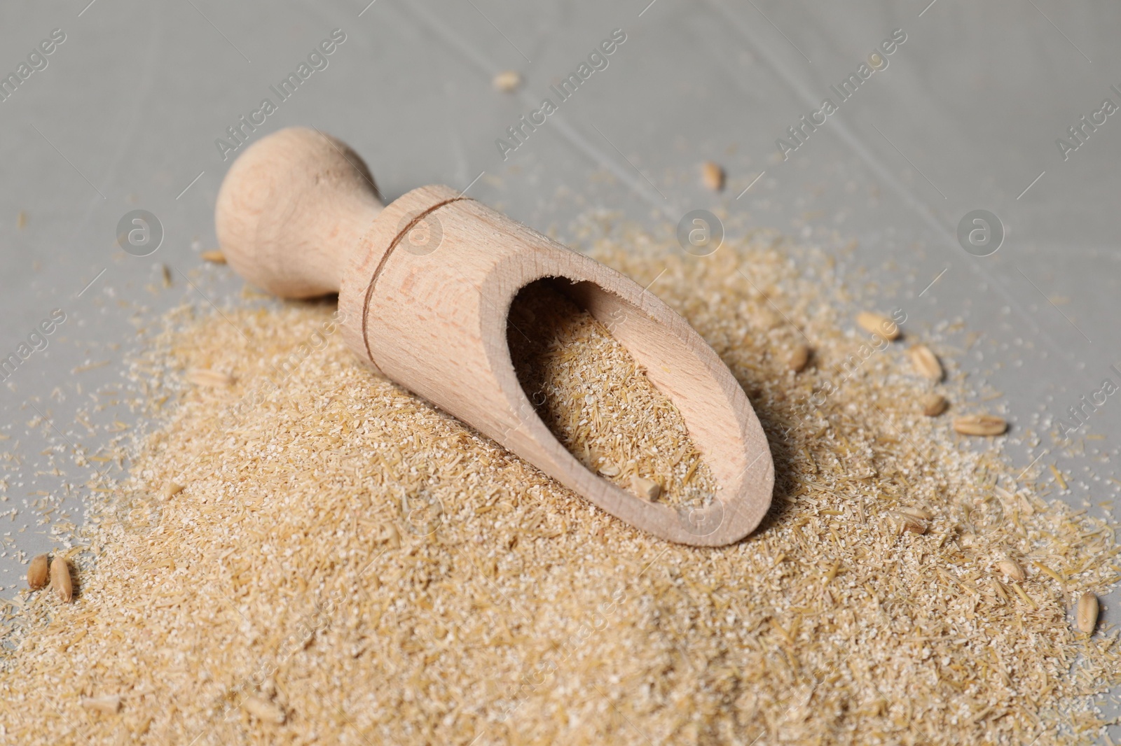 Photo of Oat bran in scoop on grey table, closeup