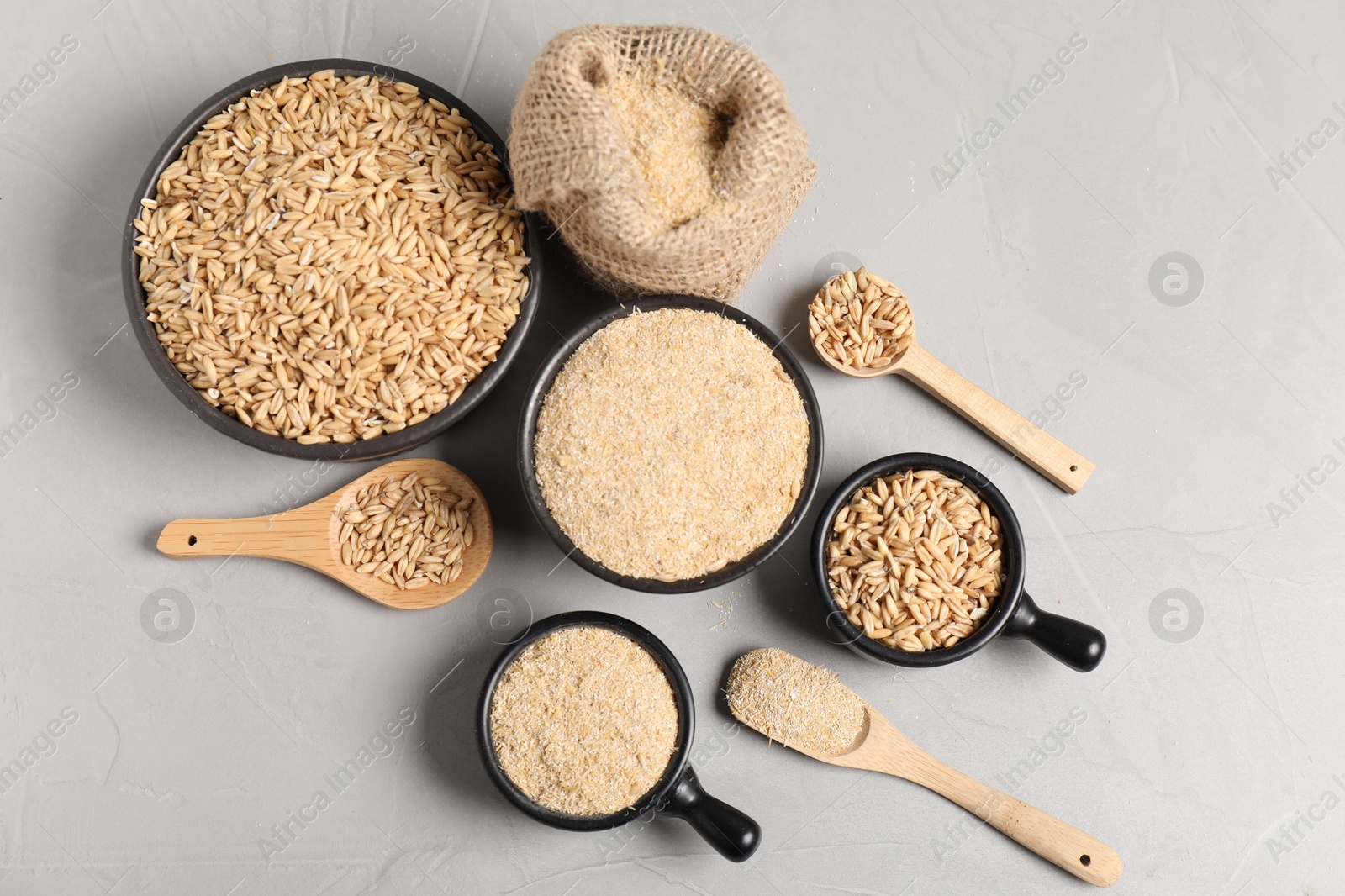 Photo of Oat bran and grains on grey table, flat lay