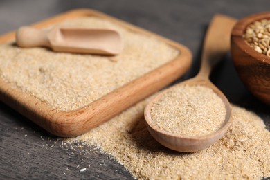 Photo of Oat bran in wooden spoon and grains on grey table, closeup