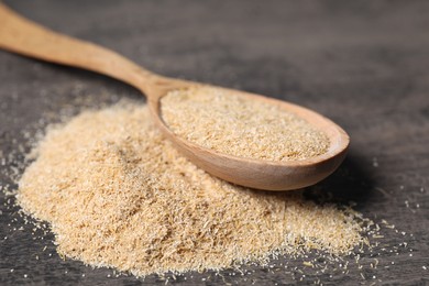 Photo of Oat bran in wooden spoon on grey table, closeup