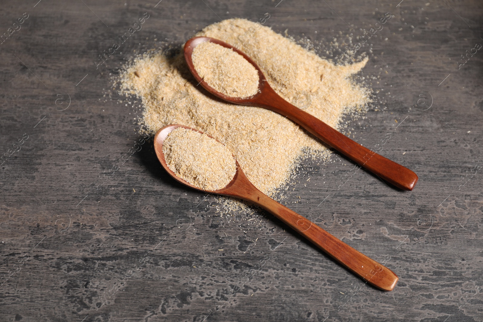 Photo of Oat bran in wooden spoons on grey table