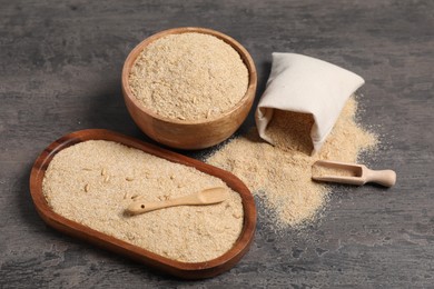 Photo of Oat bran in bowl, spoon, scoop and burlap bag on grey table