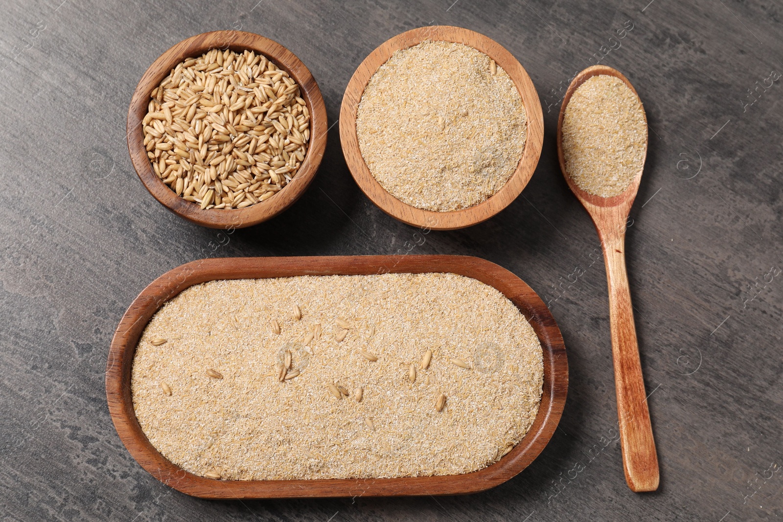 Photo of Oat bran and grains on grey table, flat lay