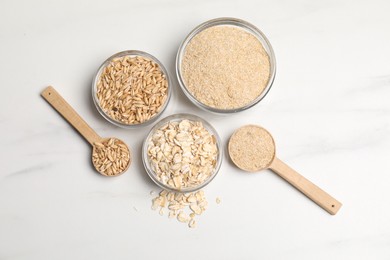 Photo of Oat bran, grains and flakes on white marble table, flat lay