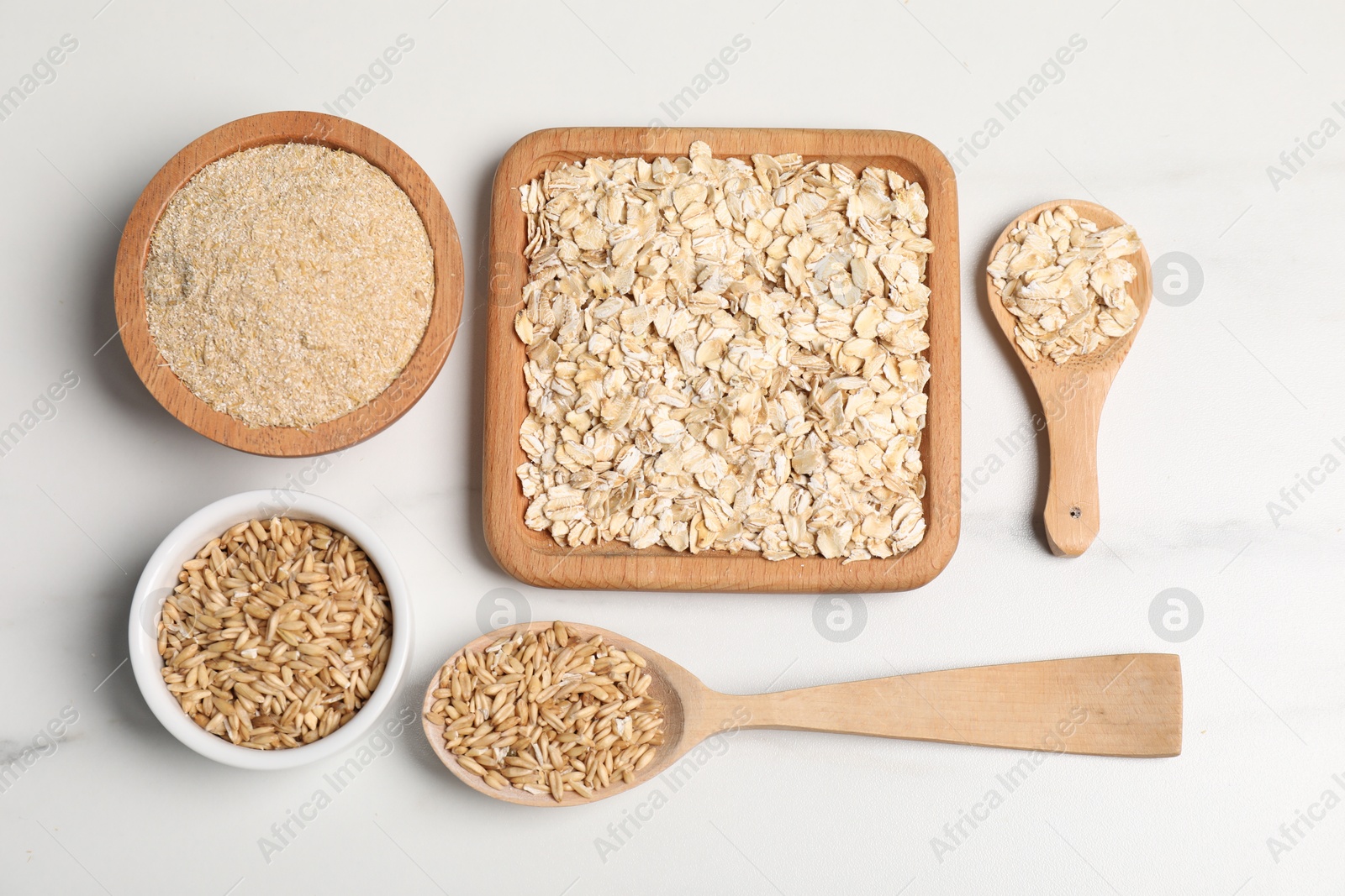 Photo of Oat bran, grains and flakes on white marble table, flat lay