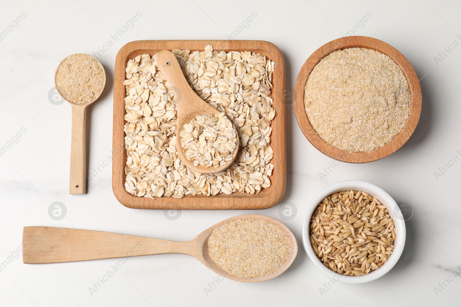 Photo of Oat bran, grains and flakes on white marble table, flat lay