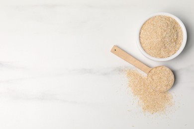 Photo of Oat bran in bowl and spoon on white marble table, top view. Space for text