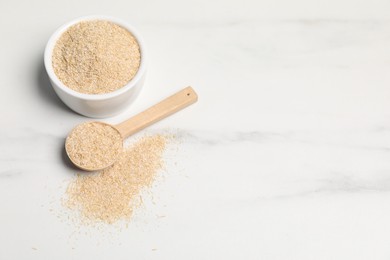 Oat bran in bowl and spoon on white marble table, space for text