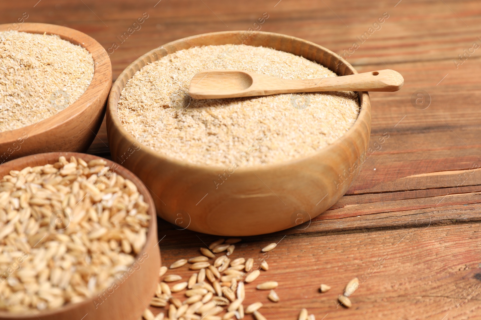 Photo of Oat bran and grains on wooden table, closeup