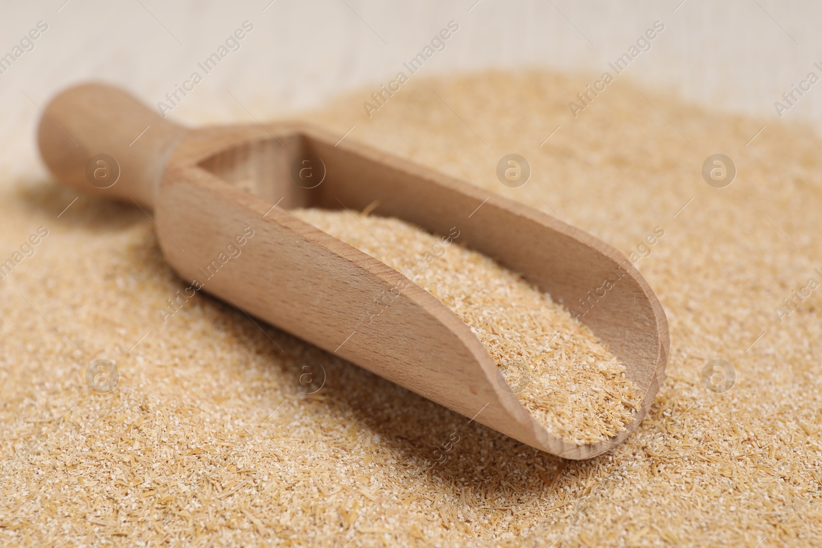 Photo of Pile of oat bran and wooden scoop on table, closeup