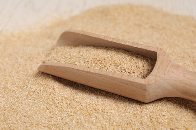 Photo of Pile of oat bran and wooden scoop on table, closeup