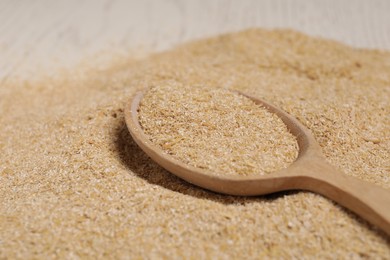 Photo of Pile of oat bran and wooden spoon on table, closeup