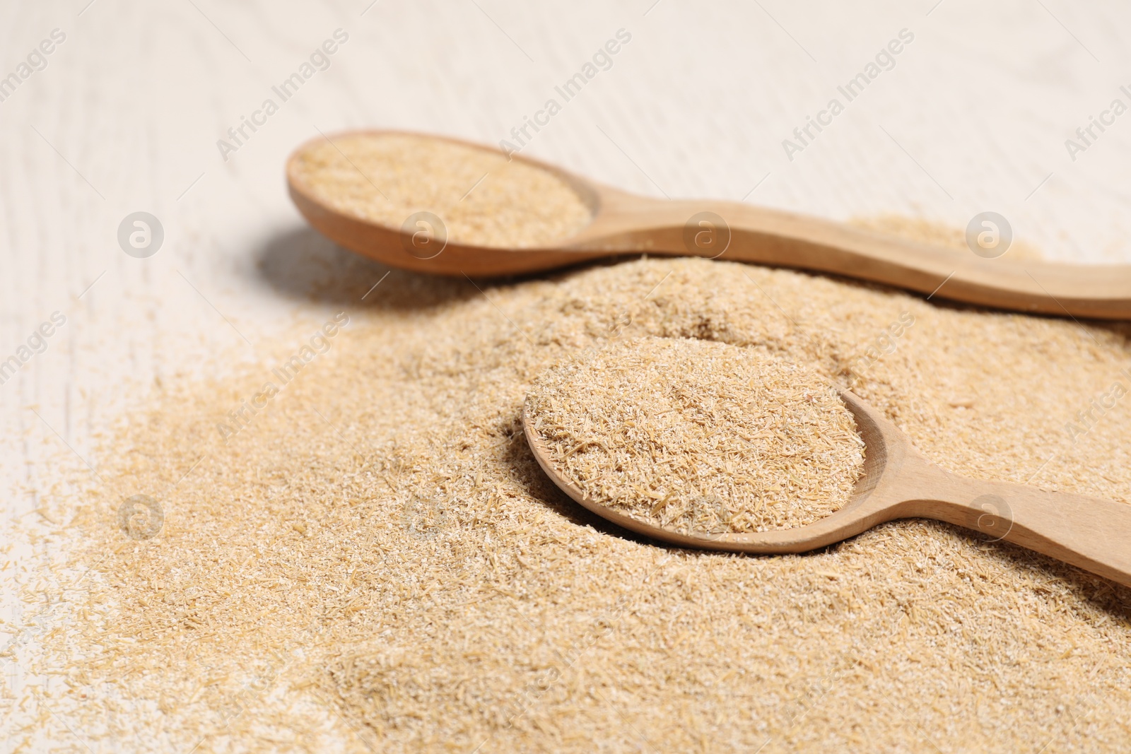 Photo of Pile of oat bran and wooden spoons on table, closeup