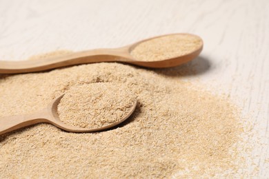 Photo of Pile of oat bran and wooden spoons on table, closeup