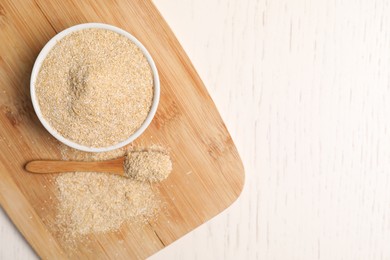 Photo of Oat bran in bowl and spoon on light wooden table, top view. Space for text