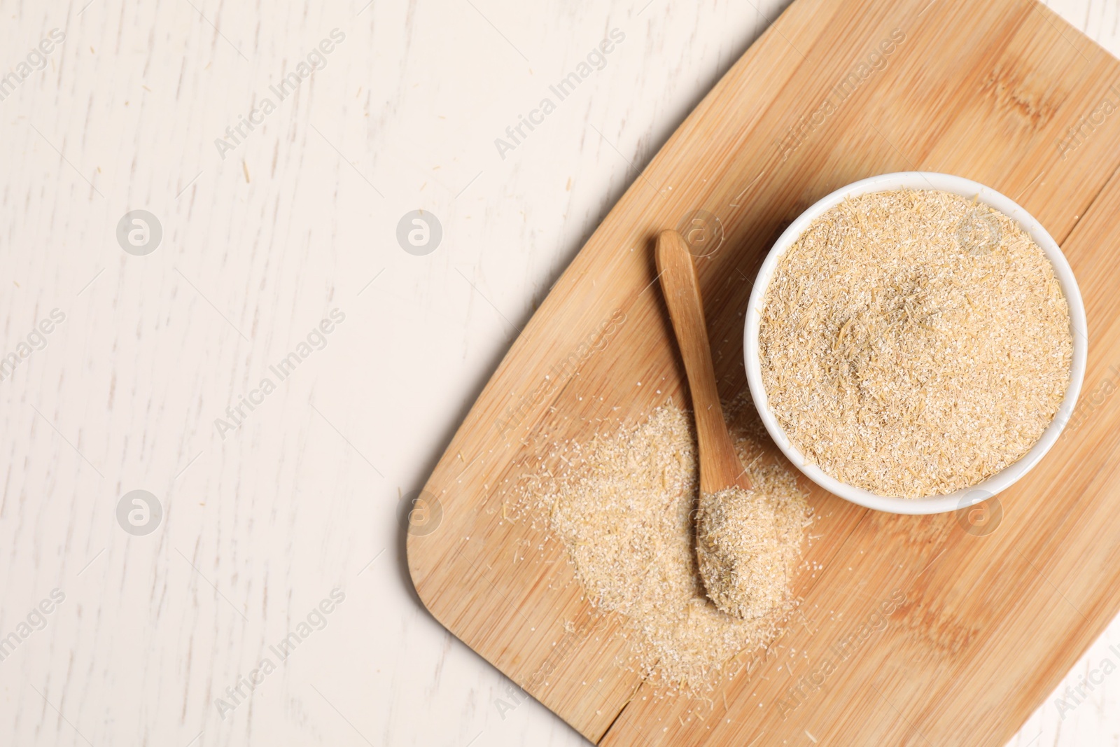 Photo of Oat bran in bowl and spoon on light wooden table, top view. Space for text