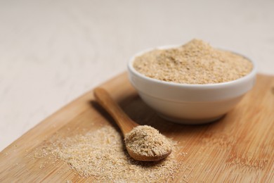 Photo of Oat bran in bowl and spoon on light table, closeup