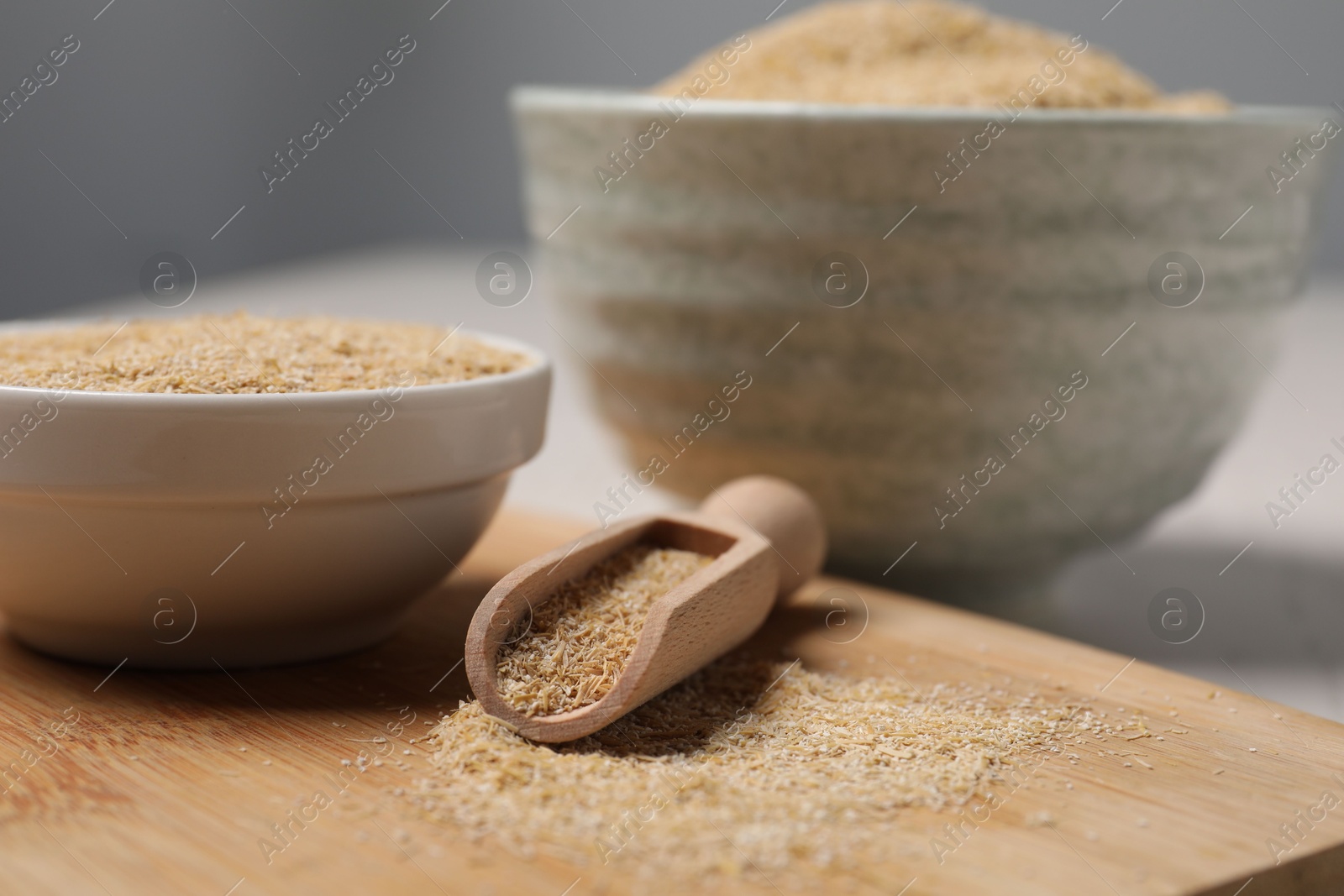 Photo of Oat bran in bowls and scoop on table, closeup