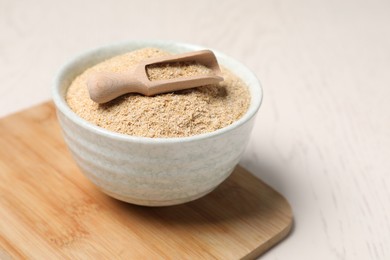 Photo of Oat bran in bowl and scoop on light table, closeup