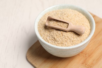 Photo of Oat bran in bowl and scoop on light table, closeup