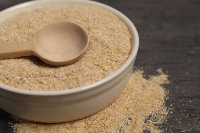 Photo of Oat bran in bowl and spoon on grey table, closeup