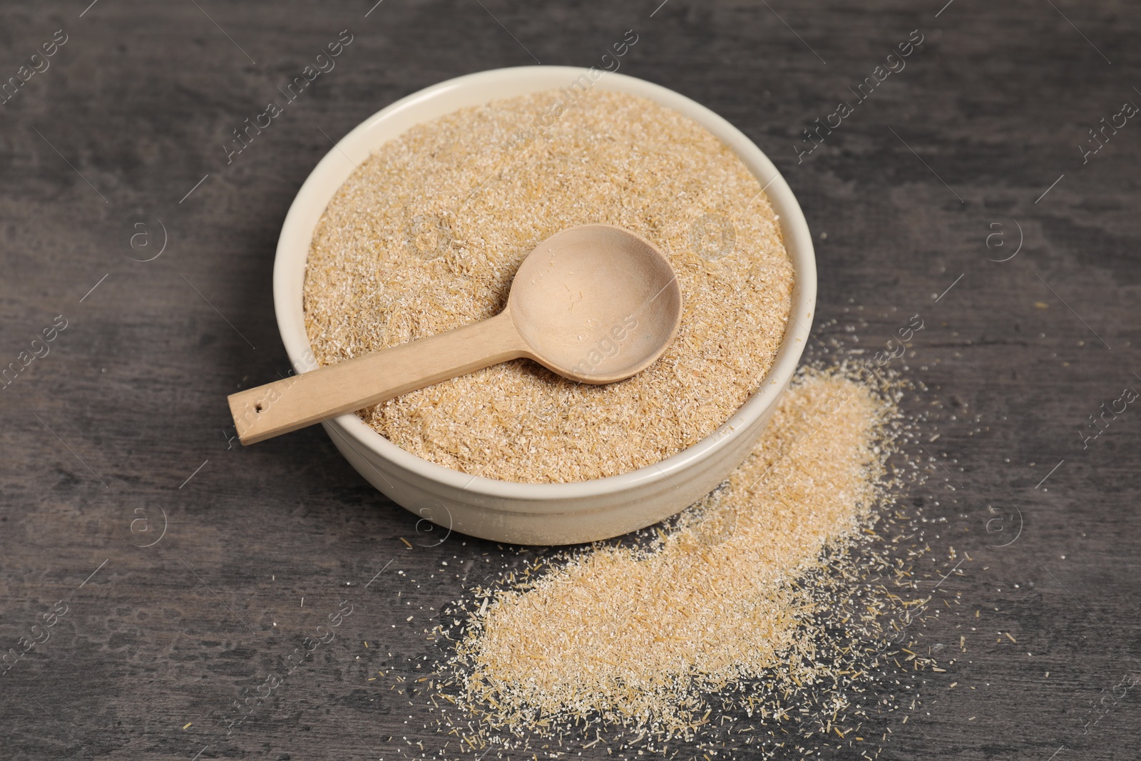 Photo of Oat bran in bowl and spoon on grey table