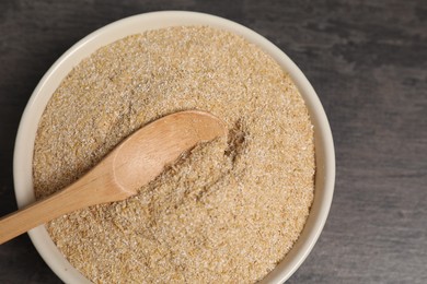 Photo of Oat bran in bowl and spoon on grey table, top view