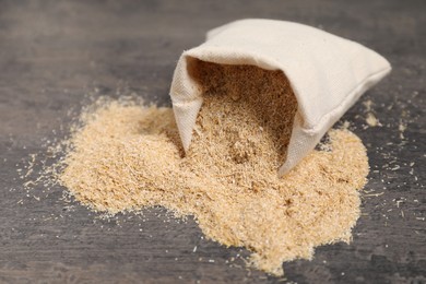 Photo of Oat bran in burlap bag on grey table, closeup