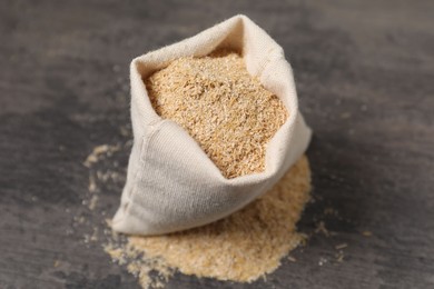 Photo of Oat bran in burlap bag on grey table, closeup