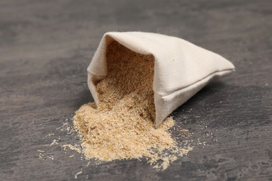 Photo of Oat bran in burlap bag on grey table, closeup