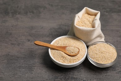 Photo of Oat bran in bowls, burlap bag and spoon on grey table, space for text