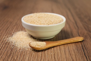 Photo of Oat bran in bowl and spoon on wooden table, closeup