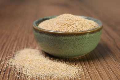 Photo of Oat bran in bowl on wooden table, closeup