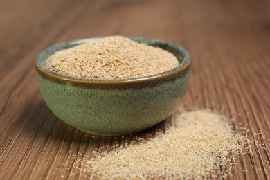 Oat bran in bowl on wooden table, closeup