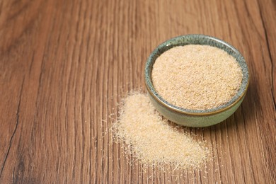 Photo of Oat bran in bowl on wooden table, closeup. Space for text