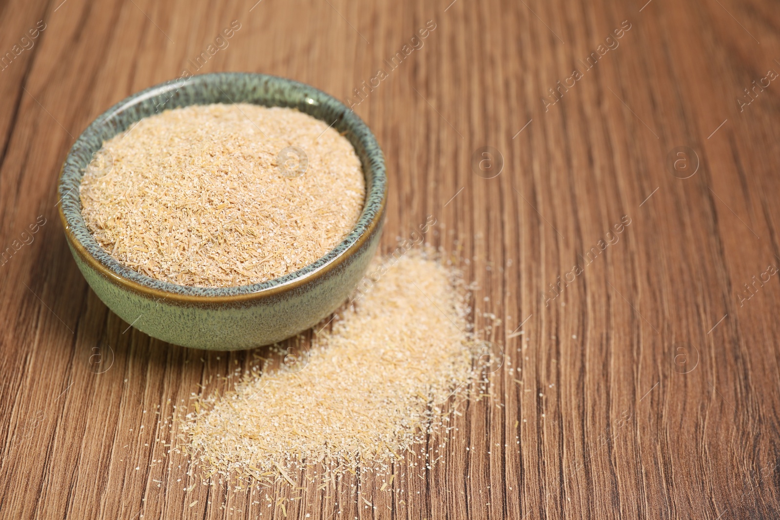 Photo of Oat bran in bowl on wooden table, closeup. Space for text