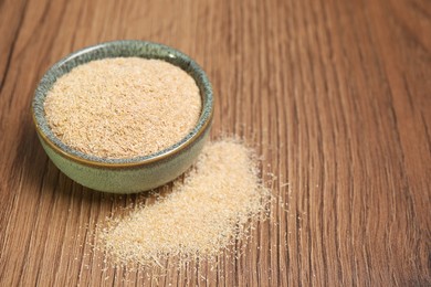 Photo of Oat bran in bowl on wooden table, closeup. Space for text