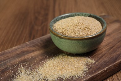 Photo of Oat bran in bowl on wooden table, closeup