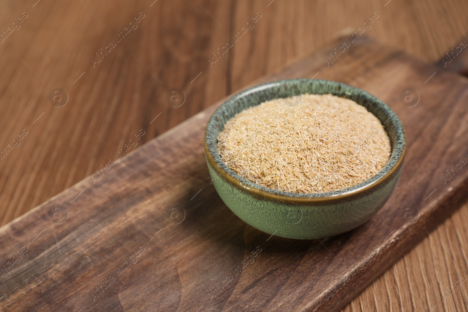 Photo of Oat bran in bowl on wooden table, closeup