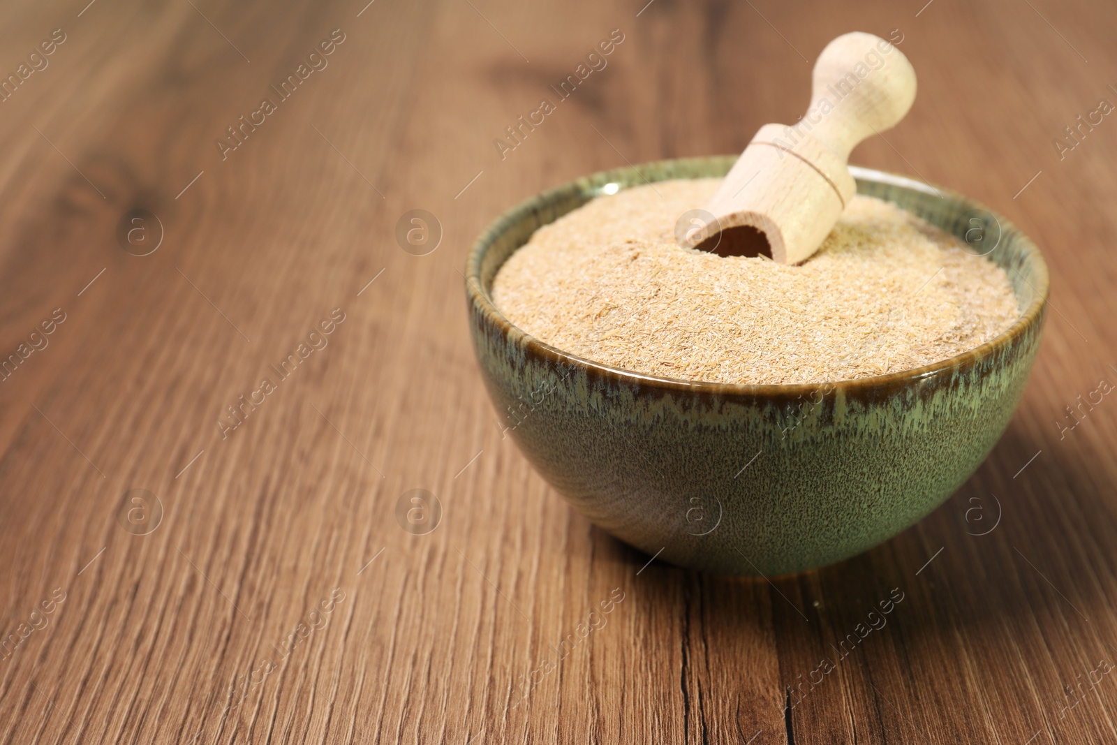 Photo of Oat bran in bowl and scoop on wooden table, closeup. Space for text