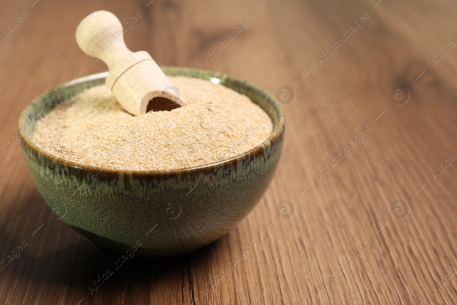 Photo of Oat bran in bowl and scoop on wooden table, closeup. Space for text