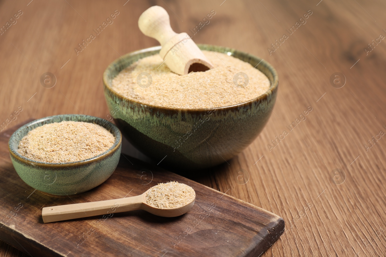 Photo of Oat bran in bowls, spoon and scoop on wooden table