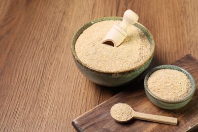 Photo of Oat bran in bowls, spoon and scoop on wooden table, space for text