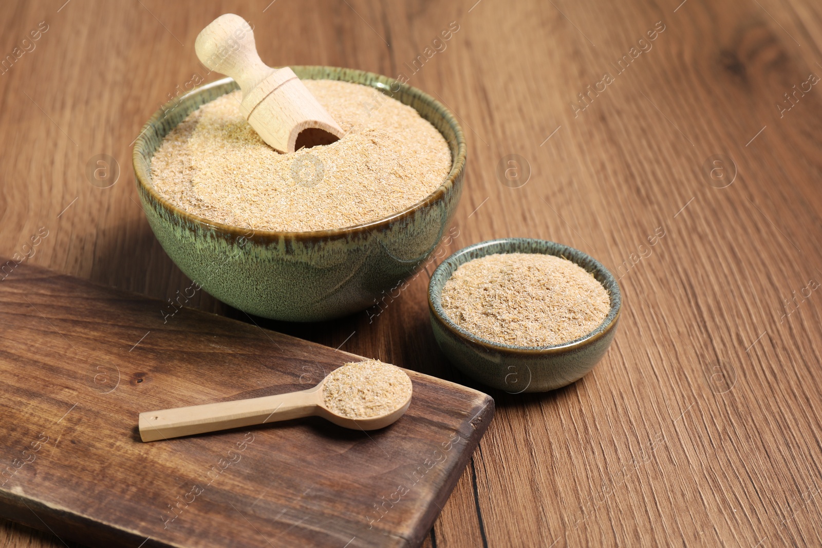 Photo of Oat bran in bowls, spoon and scoop on wooden table